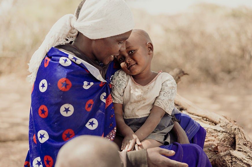 Lea holds her daughter Narukoki with love and hope. Child sponsorship has brought new light into their lives. (Tanzania, 2024) 