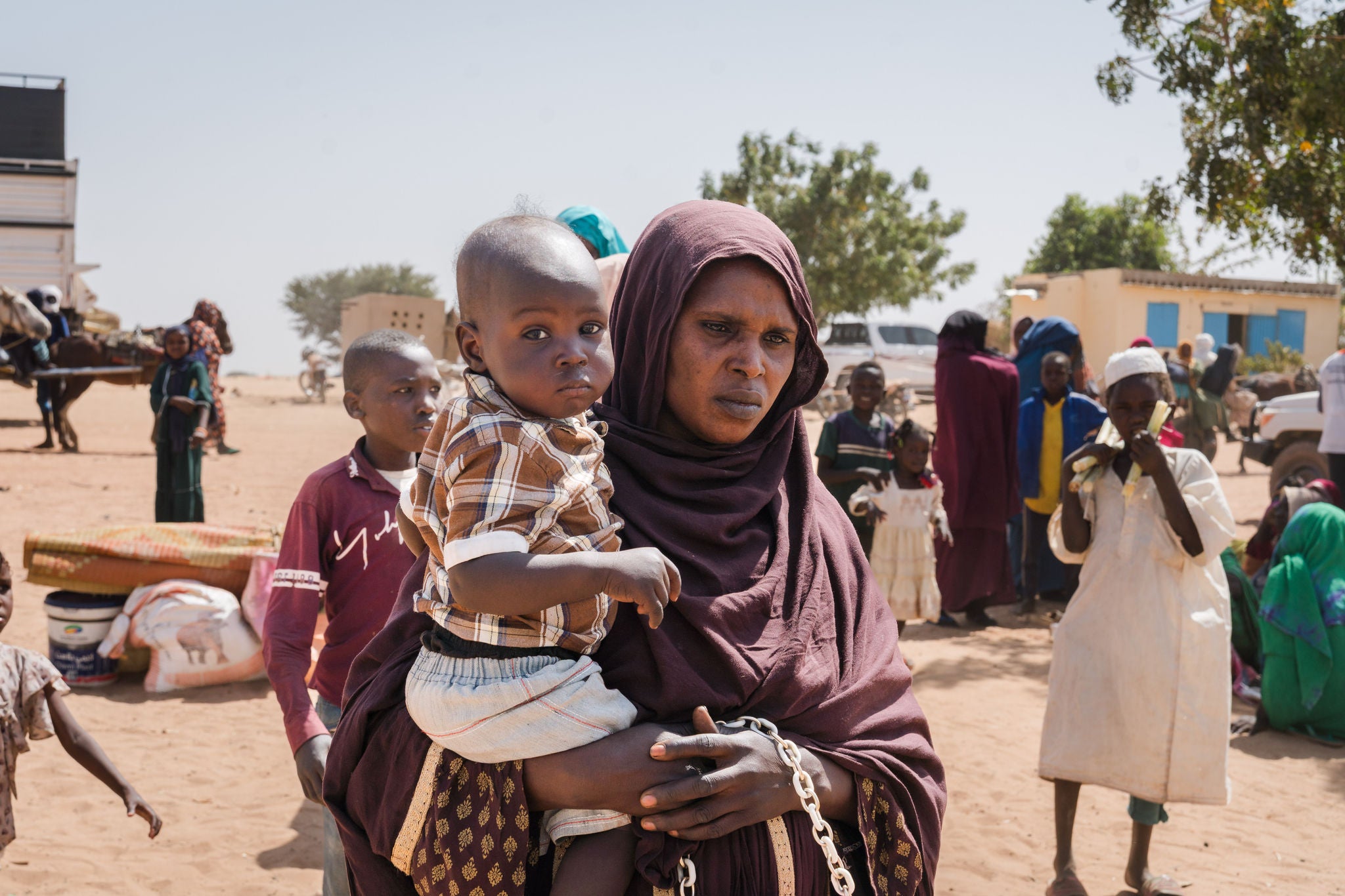 Hussana, 37, fled conflict with her husband and 5 children to Adre, Chad from Khartoum, Sudan.  It took the family one month to reach the border. “I am looking for a future,” Hussana says.  “There is no trouble in Chad.”
Hussana’s father is from Chad, and he moved to Gararef, Sudan for farming before she was born. She lived her entire life in Sudan, until now. “I want the world to help Sudan, but I don’t want to go back.”

Nearly two years after the start of the latest crisis in Sudan, families continue to cross into Chad in search of safety. Up to 200 new refugees continue to arrive each day at the border. 
Registration now takes place uphill from the bridge, where families provide information on age, household size, reasons for fleeing, and challenges faced during their journey. After registering, they receive food from the Chad Red Cross, vaccinations from MSF, and wait to be transferred to the nearby settlement. Under trees and beside tented structures, crowds of mostly women seek shade. Most arrive with very few belongings, having walked long distances while carrying children. Many report theft and violence along the way, particularly against women and girls.