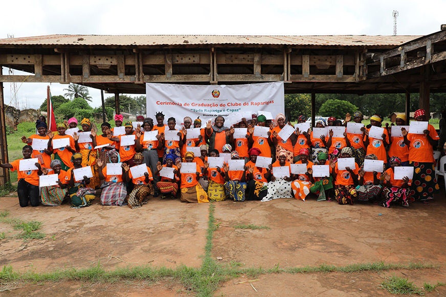 A group of young women hold up their graduation certificates.