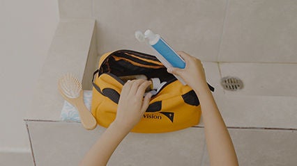 A child’s hands unpacks a World Vision hygiene kit with hair brush and toothbrush.