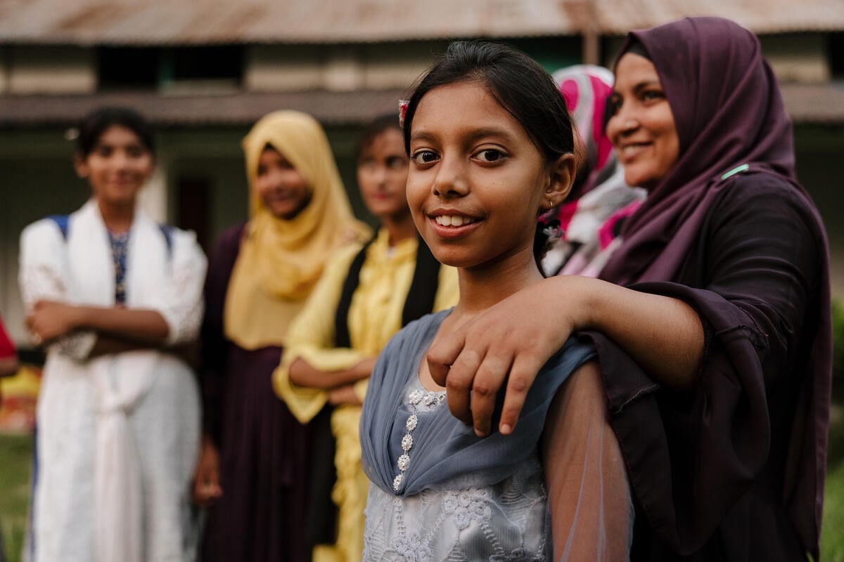A girl smiling at the camera surrounded by other happy women.