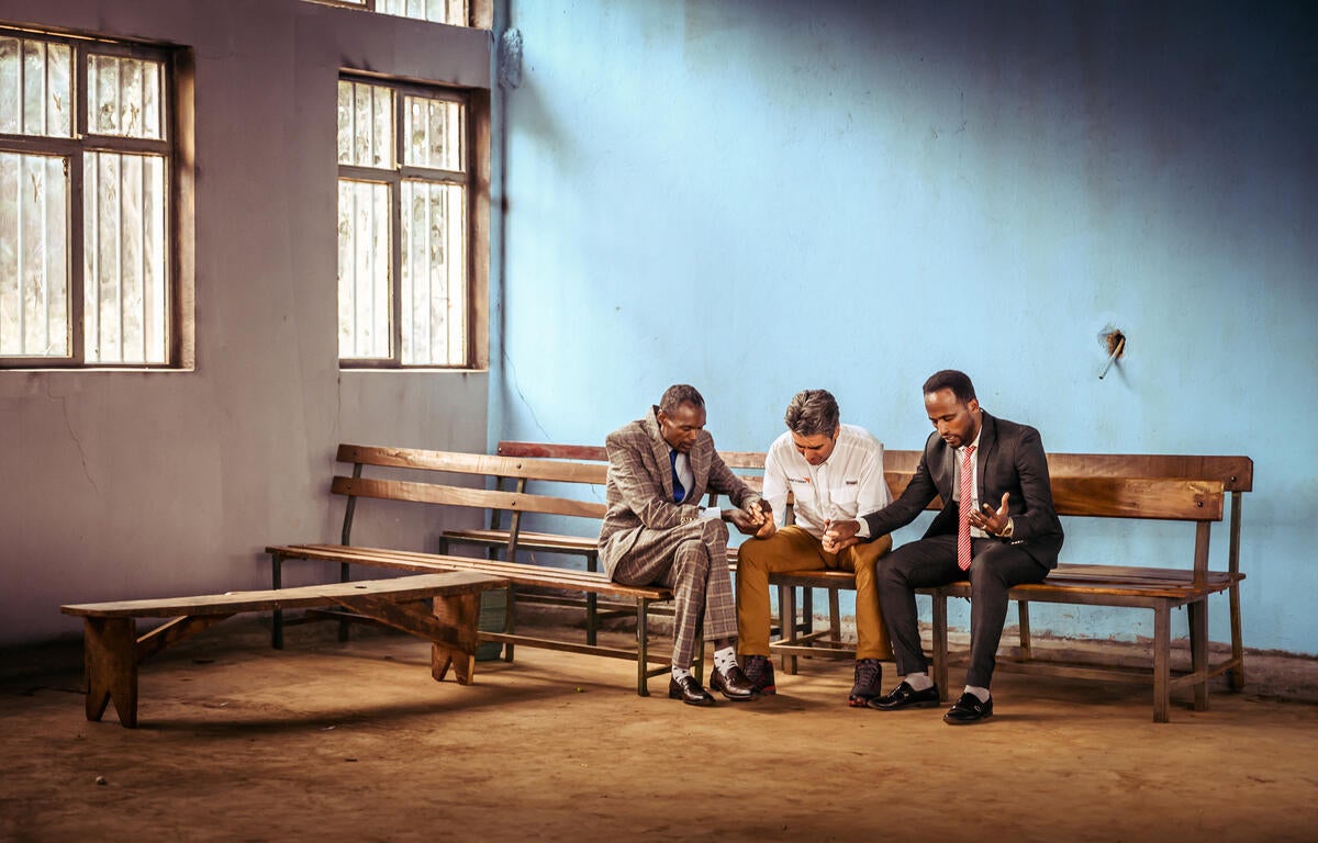 Edgar, a World Vision senior leader, prays with Pastor Abebe Morka and church elder Desalegn Bana Jaba in Ethiopia.