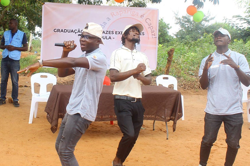 Three young men sing and dance.