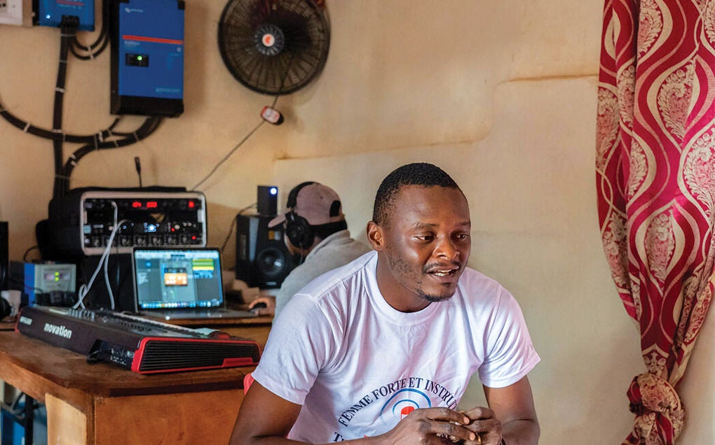 A man sits, wearing a white shirt and looks down. 