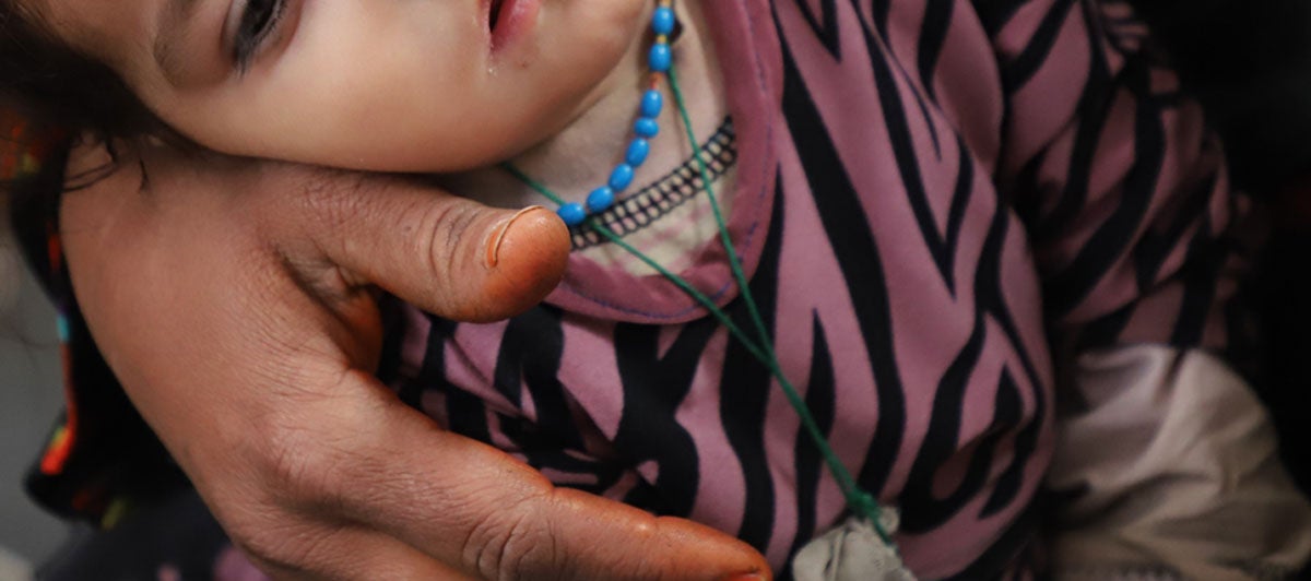Cropped photo of a small girl resting weakly in the arms of a woman.