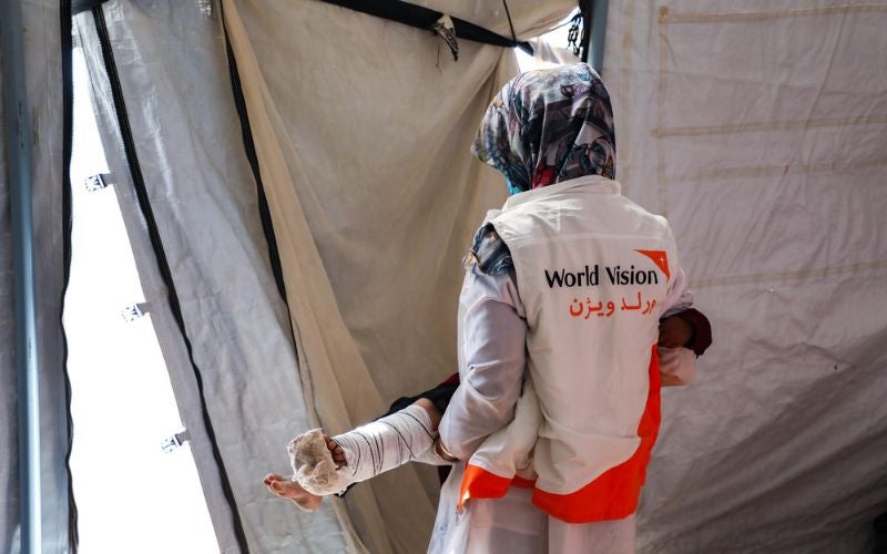 A World Vision worker carrying an injured child