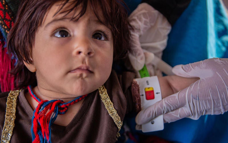 A health worker measures the circumference of a baby’s left arm.