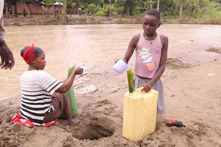 Two women collecting dirty water.