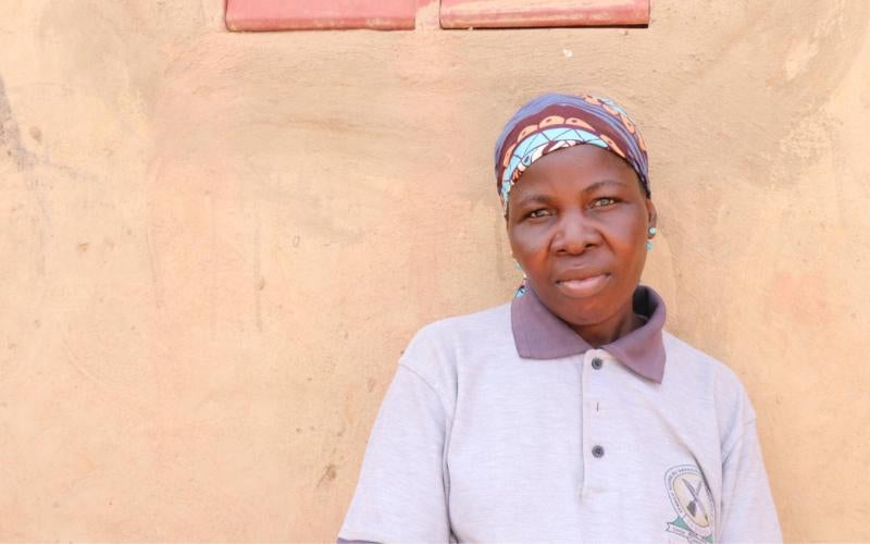 A woman who fled her home due to violence in Burkina Faso stands with a solemn expression on her face.