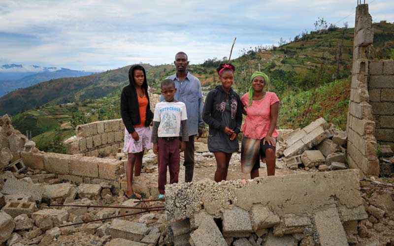 darien-gap-migrant-route-haitian-family-standing-in-building-rubble