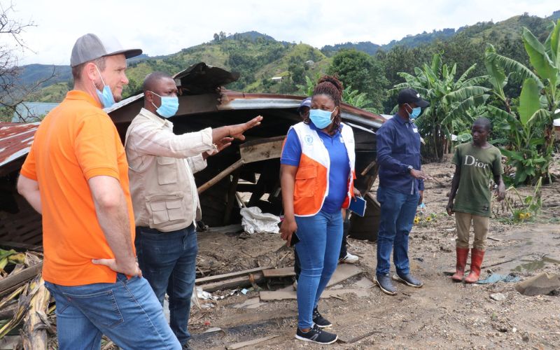 A group of people including World Vision workers are in discussion amongst destruction