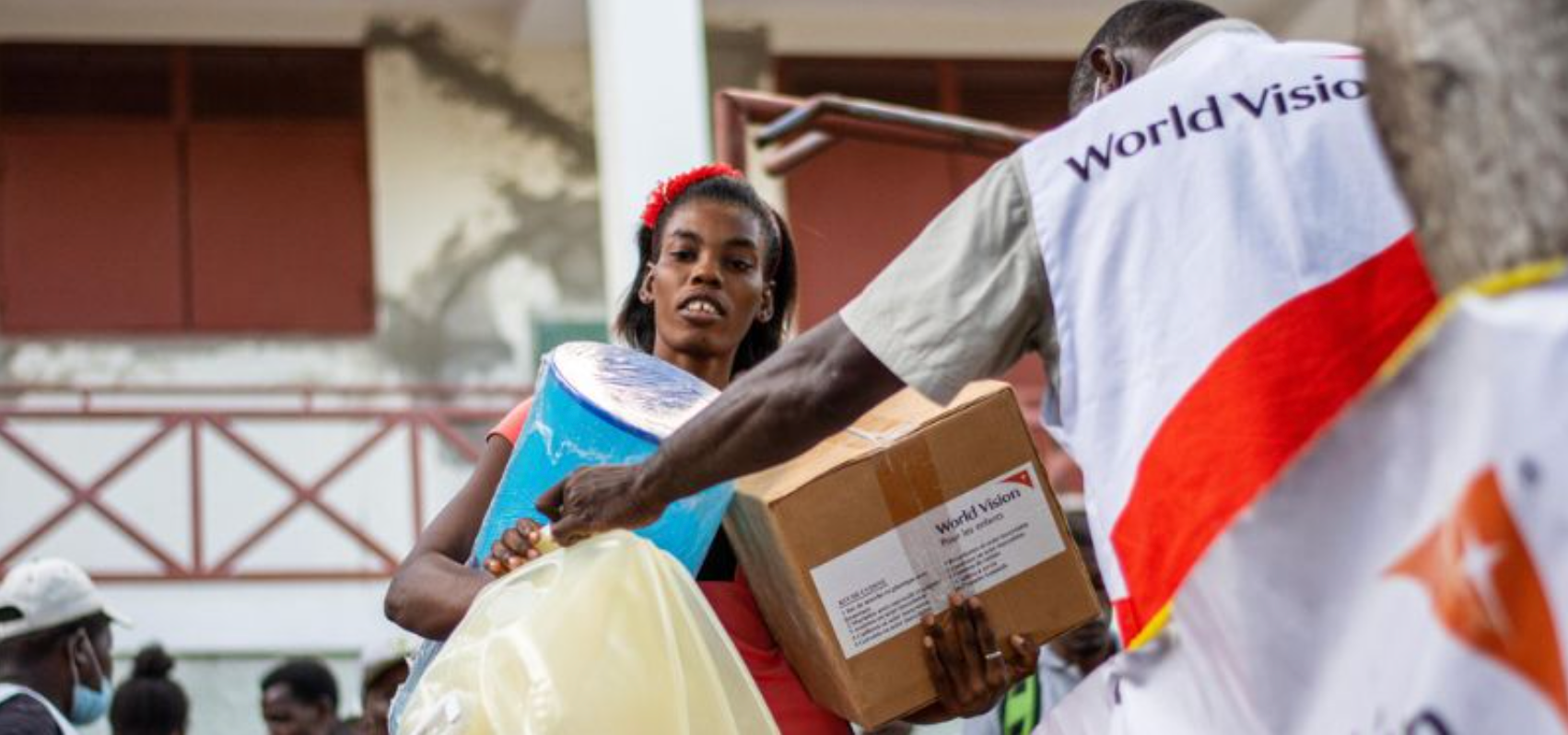 A woman carrying boxes next to a World Vision worker