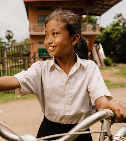 A girl looks on her side while holding bicycle handle bars. 