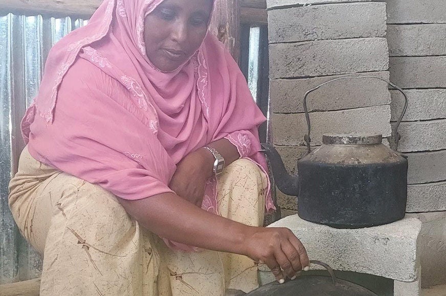 A woman shows a finished, ready-to-use energy-efficient cookstove.