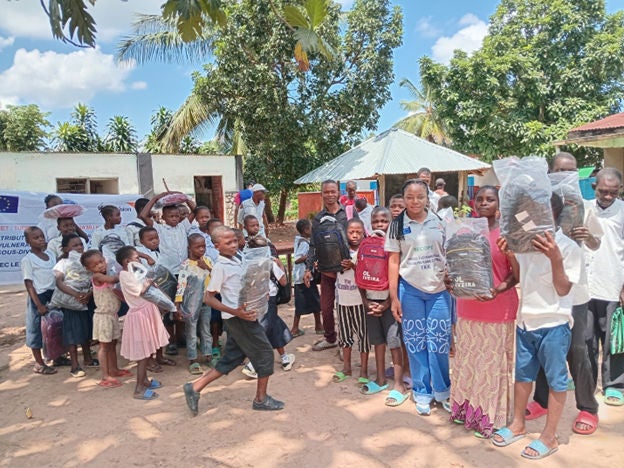 A group of children in the Democratic Republic of the Congo hold up thier new school supplies. 