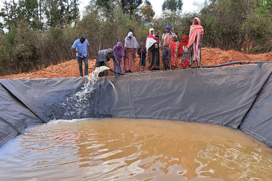 Community members store water in a geomembrane-lined pond using green, solar-powered pumps.