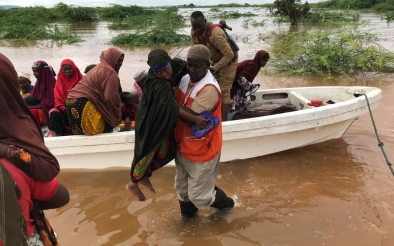 A World Vision worker lifts someone over flood waters