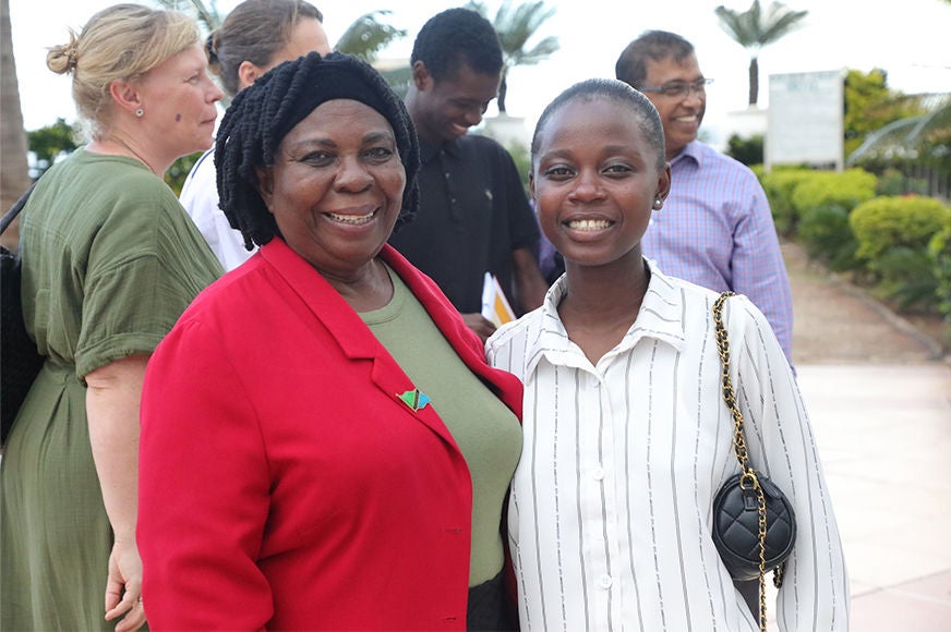 A mentor wears a red jacket and smiles alongside an adolescent girl.