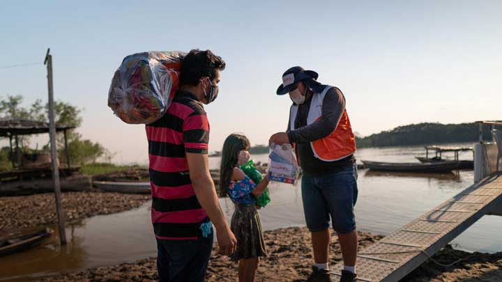 A World Vision staff hands a pack of food to a girl.