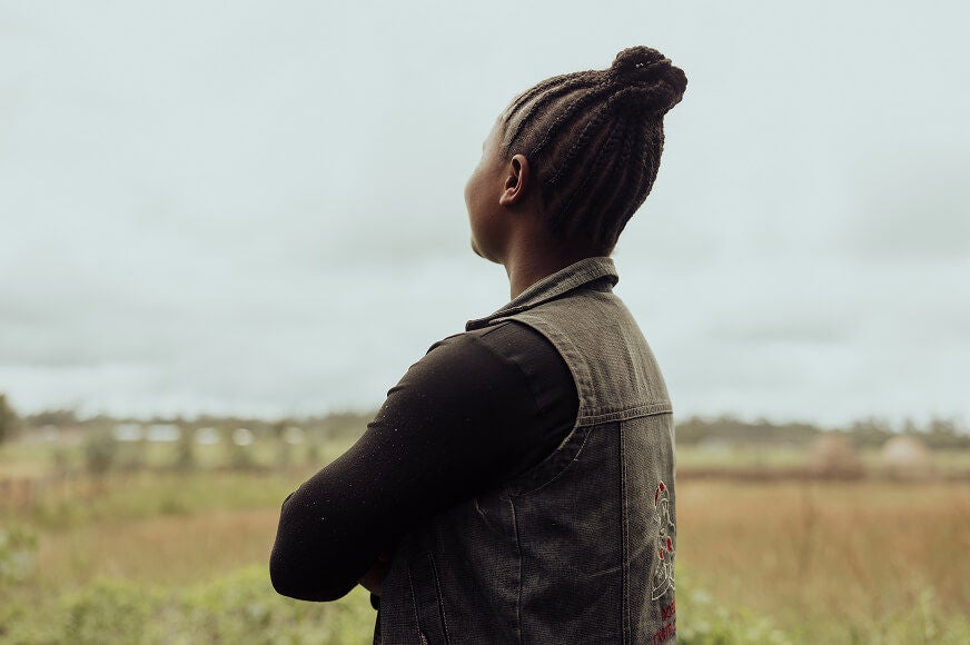 A woman confidently looks off into the distance with her arms crossed.