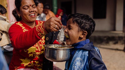 Laughing mother feeding her smiling child.
