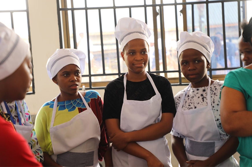 Three adolescent females wearing chef hats.