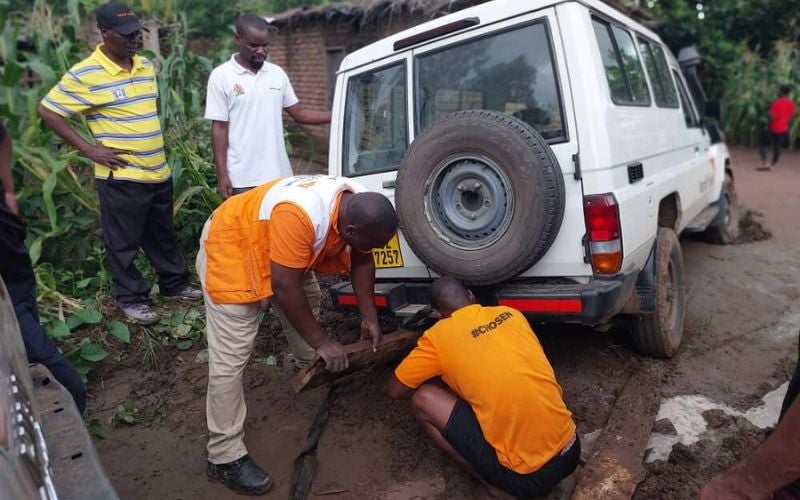 World Vision workers helping lift a van from mud