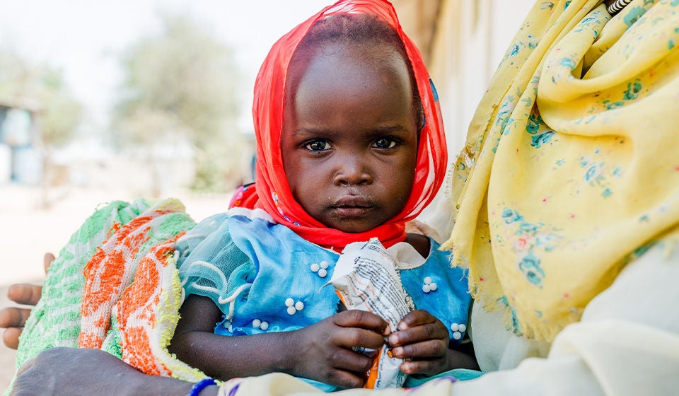 A young girl holds a ready-to-use therapeutic food packet. (Chad, 2025)