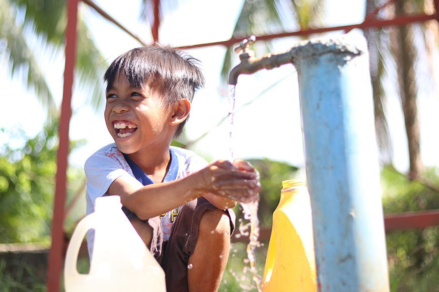 Jory laughs as he washes his hands from an outdoor faucet. Philippines, 2020