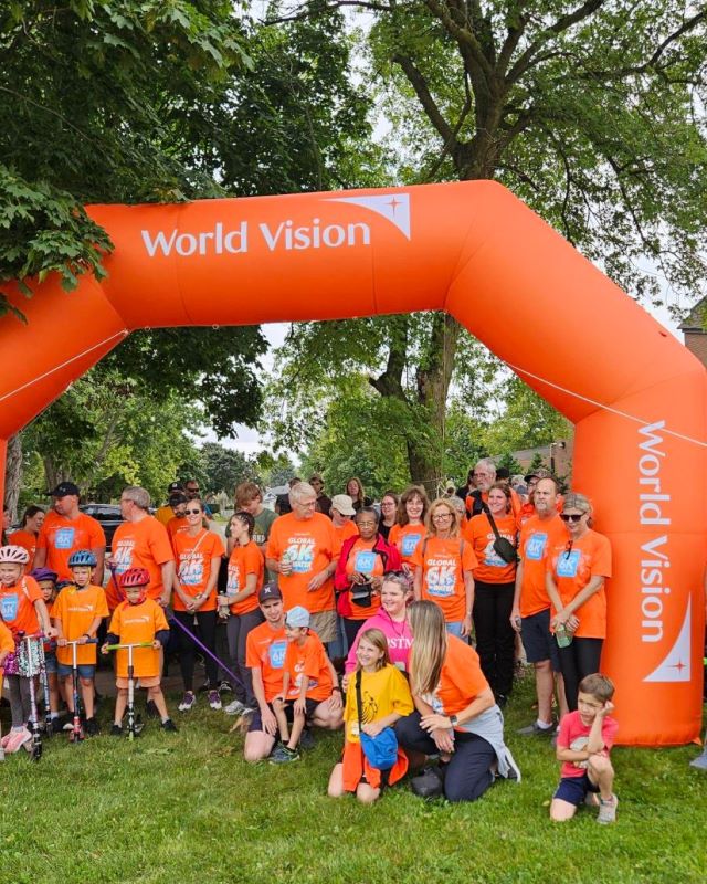 Gathered under a large orange world vision banner is a group of volunteers from the Global 6K event.