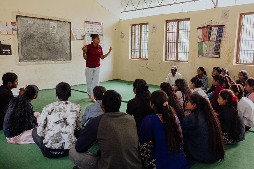 Neha speaks to a group of people inside a classroom. Through World Vision programs, she helps parents understand the importance of rejecting early marriage for their daughters.
