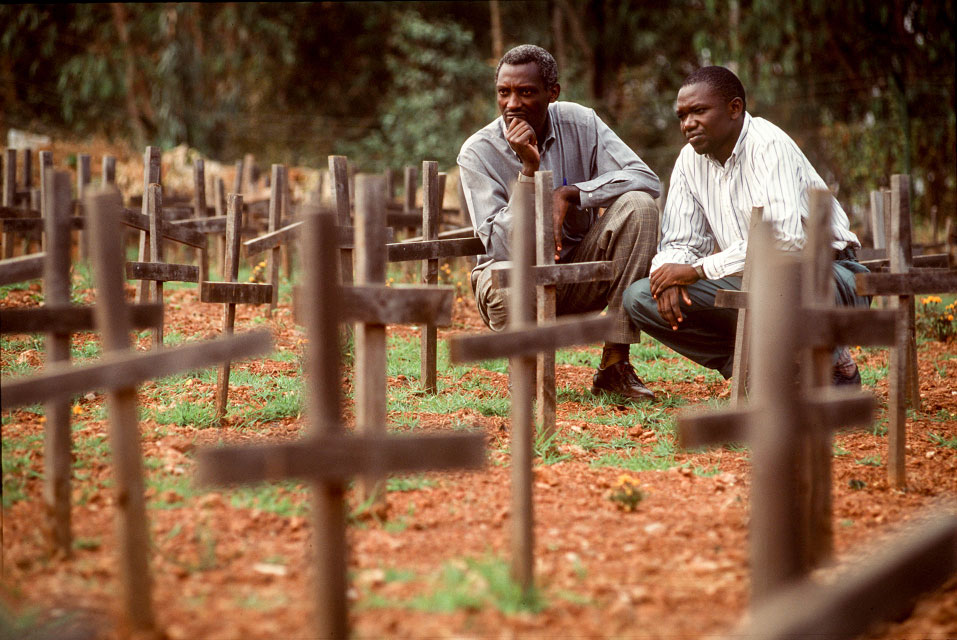 This 2001 image shows a Tutsi pastor and a Hutu teacher visiting a cemetery where 6,000 genocide victims are buried.  Photo: Jon Warren