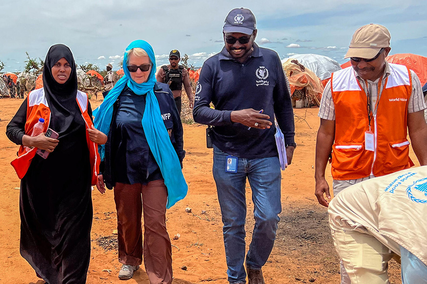 World Vision staff walking and discussing with UN staff at a refugee camp.