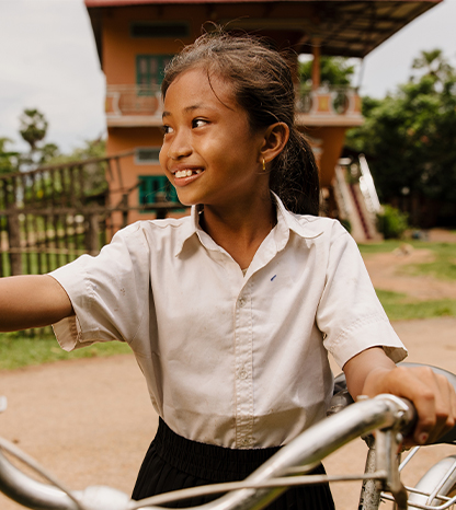 A girl looks on her side while holding bicycle handle bars. 