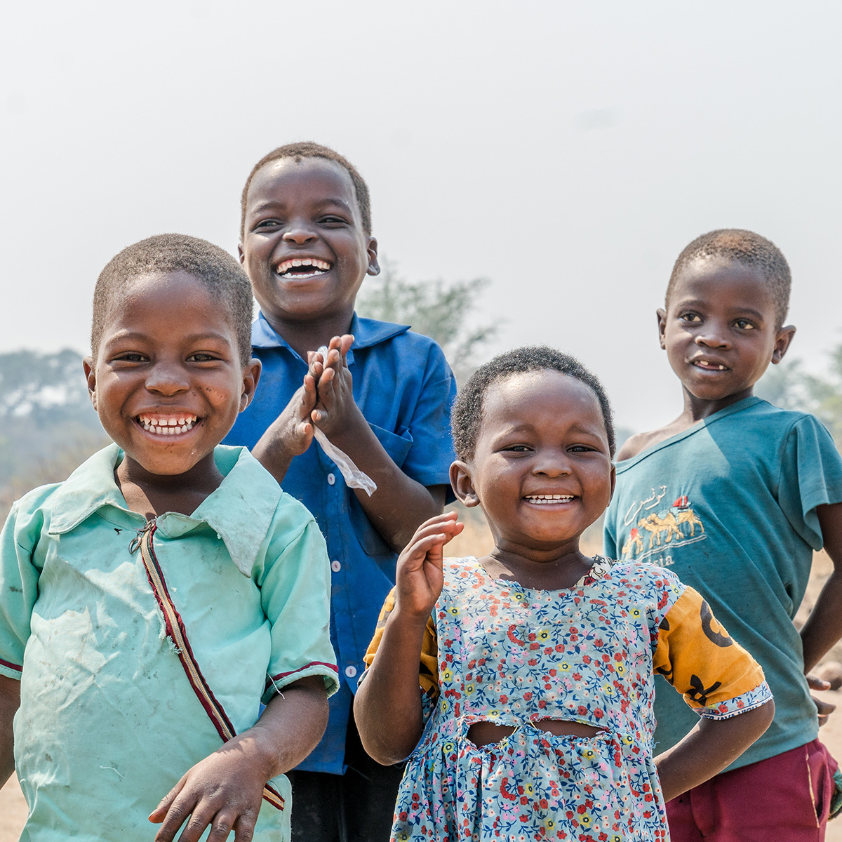 Four children dressed in blue smile towards the camera.