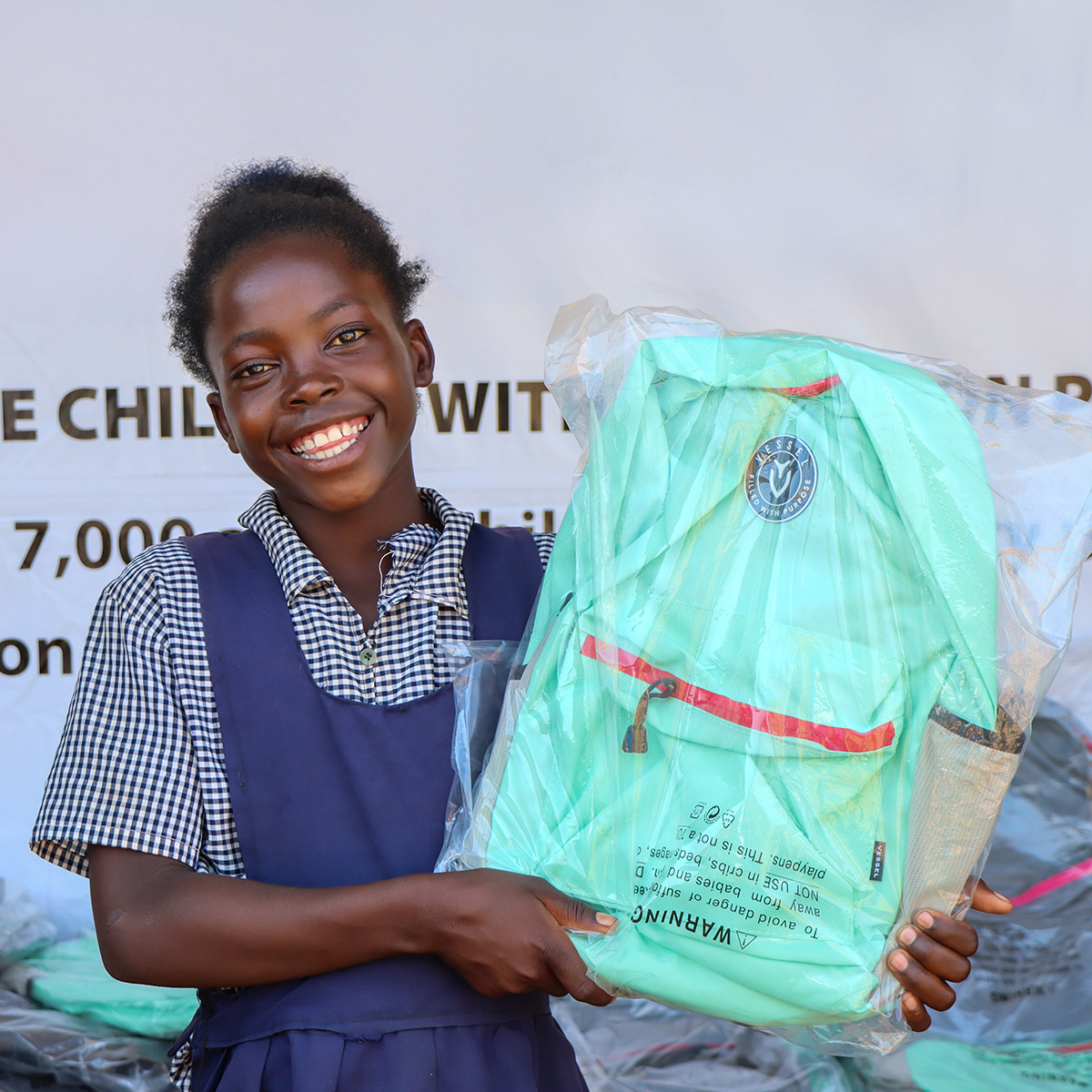 Student holding a packaged school backpack during a supply distribution event.